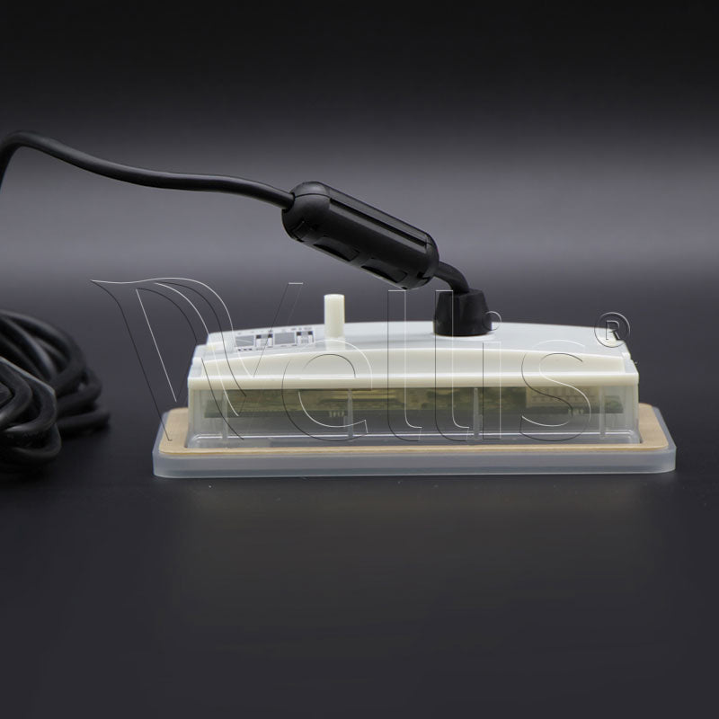 A small rectangular electronic device with a clear plastic cover, beige base, white top panel, and attached black power cord, photographed on a dark studio background.